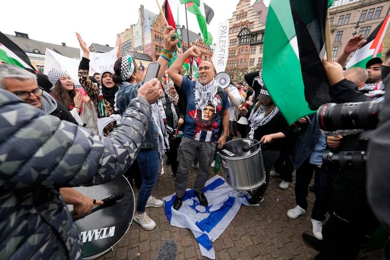 A protestor stands on.a flag of Israel during a Pro-Palestinian demonstration for excluding Israel from Eurovision ahead of the second semi-final at the Eurovision Song Contest in Malmo, Sweden, Thursday, May 9, 2024. (AP Photo/Martin Meissner)
