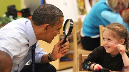 President Barack Obama uses a spy glass to play with a Decatur student during a 2013 visit to Georgia. JOHNNY CRAWFORD / JCRAWFORD@AJC.COM