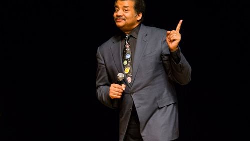 FILE - In this March 21, 2017 file photo, astrophysicist Neil deGrasse Tyson presents a lecture at the Morris Performing Arts Center in South Bend, Ind. Tyson has a suggestion for anyone with a view of next week's solar eclipse: Put down your smartphone and take in the phenomenon yourself. Tyson told an audience to "Experience this one emotionally, psychologically, physically," at New York's American Museum of Natural History on Monday Aug. 14, 2017. The Aug. 21 event will be the first total solar eclipse in 99 years to cross a coast-to-coast swath of the United States. (Michael Caterina/South Bend Tribune via AP, File)