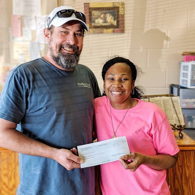 Peter Bufkin of Firebox Initiative gives a check to Tia Reed, the owner of Sista's Kitchen, after she had a fire in her home. Courtesy of Firebox Initiative