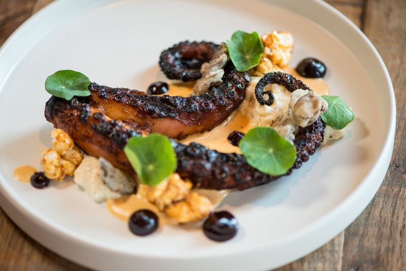  BBQ Octopus with crispy maitake, emmental grits, popcorn, harissa, and red cabbage puree. Photo credit- Mia Yakel.