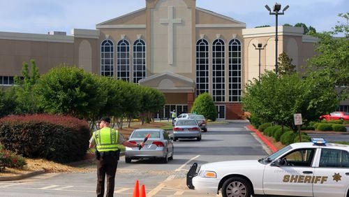 A Cobb County Sheriff's deputy directs traffic into Trinity Chapel Church of God where Jim Bolin was to be reinstalled on Sunday, June 9 , 2013, in Powder Springs.