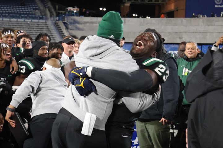 Collins Hill defensive lineman Asani Redwood (23) celebrates with an assistant coach after their 24-8 win against Milton in the Class 7A state title football game at Georgia State Center Parc Stadium Saturday, December 11, 2021, Atlanta. JASON GETZ FOR THE ATLANTA JOURNAL-CONSTITUTION