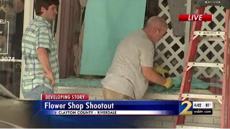 Employees clean up a broken shop window at a popular Riverdale florist after a shooting Thursday.