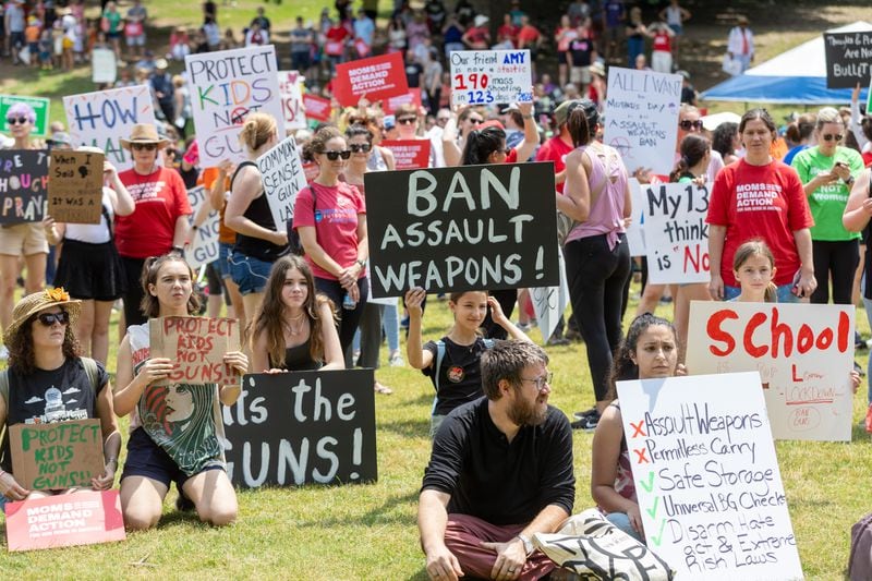 People hold up signs at a rally organized by Georgia Moms Demand Action in Piedmont Park Saturday, May 13, 2023. The rally was part of a national series of protests the day before Mother’s Day to highlight the mounting toll of gun violence.  (Steve Schaefer/steve.schaefer@ajc.com)