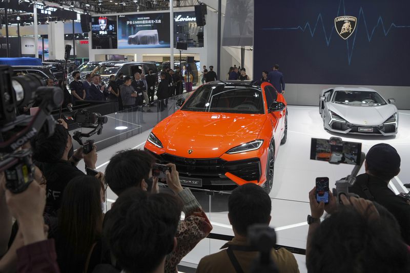 Visitors photograph a Lamborghini car during the opening of China Auto Show in Beijing, China, Thursday, April 25, 2024. (AP Photo/Tatan Syuflana)
