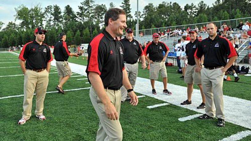 Allatoona head coach Gary Varner (foreground) smiles as he talks with his staff prior to the game. When Cobb County went through budget woes, the entire Allatoona High coaching staff was initially dismissed.
