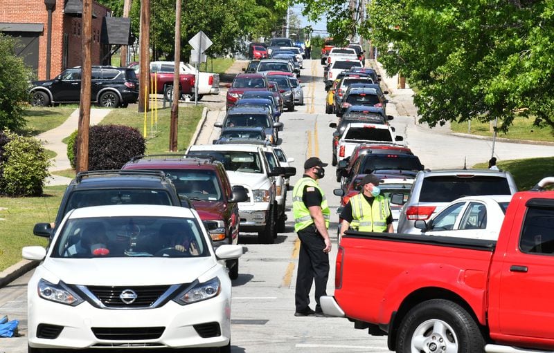 Police officers control traffic as motorists and their passengers wait to get tested at two drive-through COVID-19 testing sites at Good News Clinic in Gainesville on Tuesday, April 28, 2020. Northeast Georgia Health System partnered with Good News Clinic to test more than 300 Hall County adults and children for COVID-19. (Hyosub Shin / Hyosub.Shin@ajc.com)
