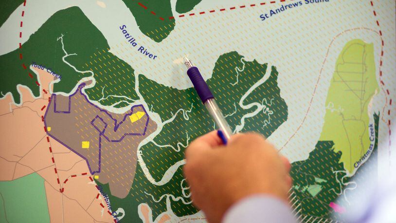 A Glynn County resident points to the mouth of the Satilla River near where the proposed spaceport will be located during a public hearing. The FAA recently released environmental impact study about the potential site, in brown to the left, for a spaceport in Kingsland, Georgia. The yellow marks indicate where rockets will be launched and land if approved by the FAA. (AJC Photo/Stephen B. Morton)