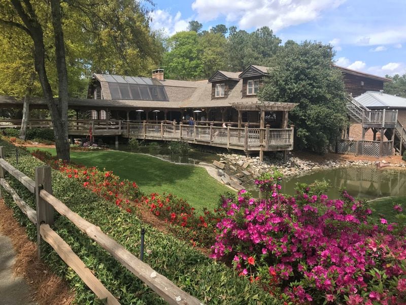 Sconyers Bar-B-Que makes its home in a massive two-story log cabin that seats 400 people. The grounds feature a pond as well as various old farm equipment. LIGAYA FIGUERAS / LFIGUERAS@AJC.COM