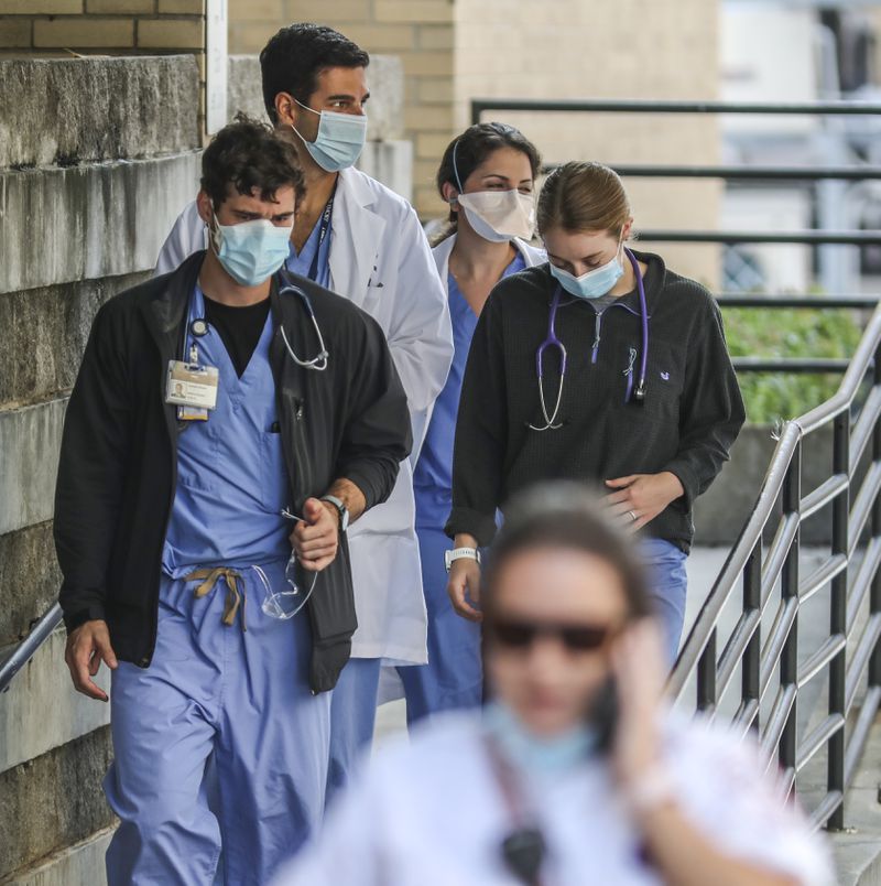 Medical workers move between buildings at Grady Memorial Hospital in downtown Atlanta last week. Already, metro Atlanta hospitals are over capacity, deluged by patients and short of staff. (PHOTO by John Spink / John.Spink@ajc.com)