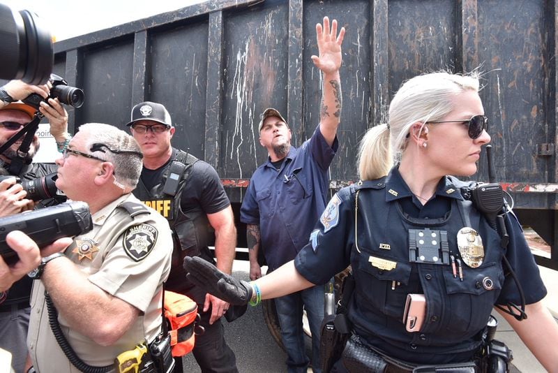An apparent participant in the neo-Nazi rally is flanked by media and law enforcement officers at the start of the event Saturday in Newnan, Ga.