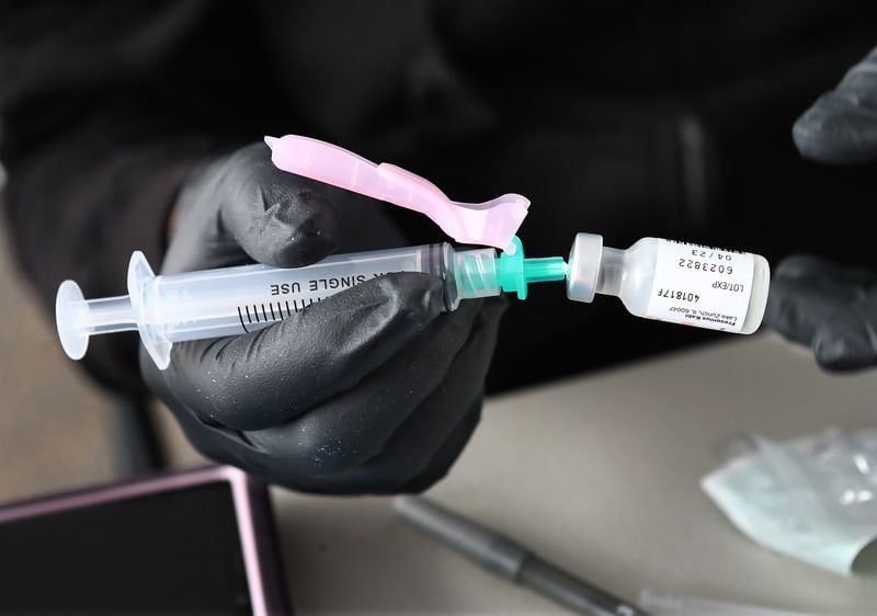 A health care worker prepares a Pfizer booster shot at a Viral Solutions drive-up COVID vaccinations and testing site on North Druid Hills Road in Atlanta on Dec 16. (Curtis Compton / Curtis.Compton@ajc.com)