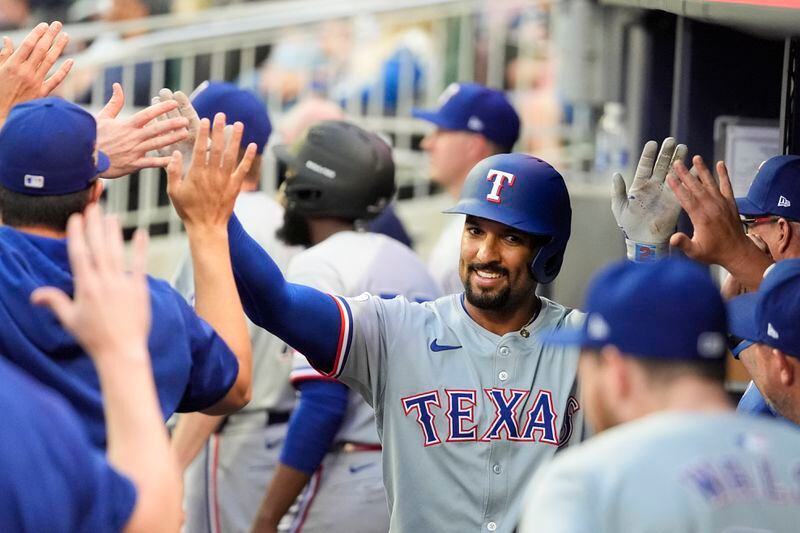 Texas Rangers' Marcus Semien celebrates with teammates in the dugout after hitting a solo home run in the frist inning of a baseball game against the Atlanta Braves Friday, April 19, 2024, in Atlanta. (AP Photo/John Bazemore)