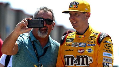 NASCAR driver Kyle Busch, right, smiles as he poses for a photograph while walking to the garage at Charlotte Motor Speedway in Concord, N.C., on May 27, 2017. (Jeff Siner/Charlotte Observer/TNS)
