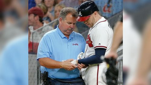 Atlanta Braves first baseman Freddie Freeman (5) has his hand examined by trainer Jim Lovell after he was hit by a pitch Wednesday, May 17, 2017, in Atlanta.