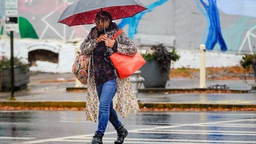 A woman crosses the road with an umbrella as rain falls in Atlanta for the first time in weeks on Tuesday. (Ben Hendren for the Atlanta Journal-Constitution)