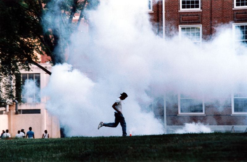 May 1, 1992: A lone student runs across the campus grounds of Clark-Atlanta University as the tear gas cannister explodes in an attempt to disperse crowds of students. (W.A. Bridges Jr/AJC staff)
