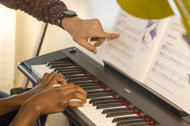 MaKhi Haynes receives a piano lesson from James Shealy, a music instructor, during an afternoon session of the Kevin Baker Music Program in Atlanta. REANN HUBER / REANN.HUBER@AJC.COM