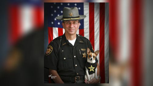 This 2006 image provided by John Hoffart shows then Sheriff Dan McClelland and his small police dog Midge at the Geauga County, Ohio, sheriff's department. Both died on Wednesday, April 14, 2021. McClelland after a lengthy battle with cancer and Midge, perhaps, of a broken heart. The family said they will be buried together. McClelland retired in 2016, after 13 years as sheriff, and 44 total in the department. The last ten with Midge, a drug-sniffing Chihuahua-rat terrier mix certified by Guinness World Records as the smallest police dog on the globe. (John Hoffart via AP)