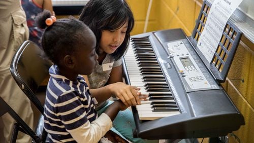 Niang Kim (right), 8, helps Esther Mupanza, 5, during lessons at Proskuneo, a music school in Clarkston that provides free lessons every Saturday morning on a variety of instruments for refugee children. Attendance for the Saturday morning Free for All can sometimes get as high as 70 kids. BRANDEN CAMP/SPECIAL