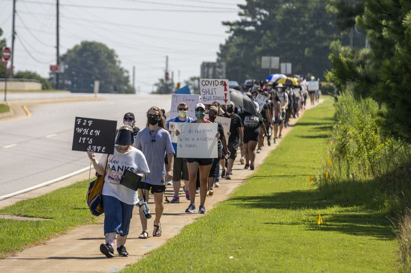 Members of the Gwinnett Educators for Equity and Justice group and their supporters carry signs as they march down Old Peachtree Road NW, in Suwanee, on July 20. (ALYSSA POINTER / ALYSSA.POINTER@AJC.COM)