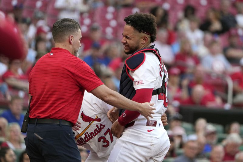 St. Louis Cardinals catcher Willson Contreras, right, is helped off the field by trainer Adam Olsen, left, after being injured during the second inning of a baseball game against the New York Mets Tuesday, May 7, 2024, in St. Louis. Contreras left the game. (AP Photo/Jeff Roberson)