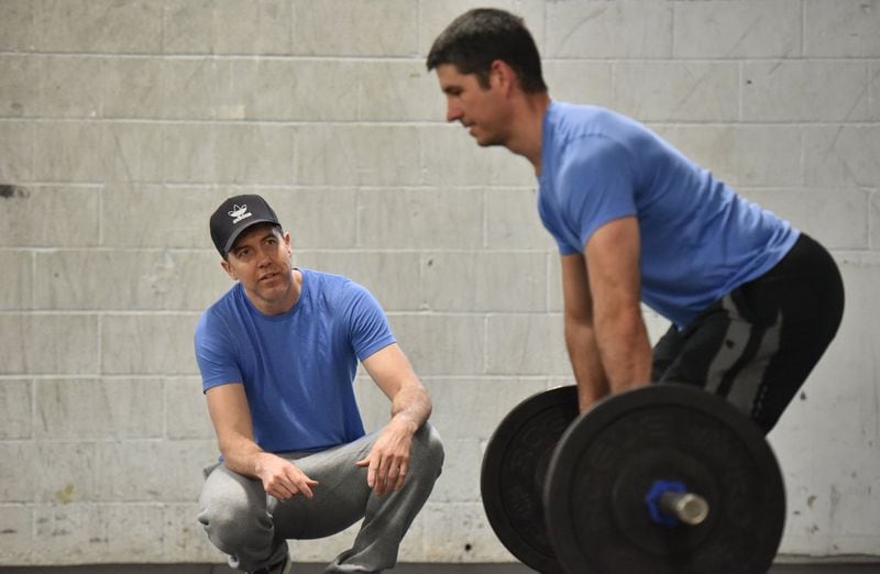 Matt Gunby (left), co-owner/trainer, instructs Mike Schuckenbrock, 43, who has been working out past 7 years and lost 40 lb, at Crossfit East Decatur on Friday, March 15, 2019. HYOSUB SHIN / HSHIN@AJC.COM