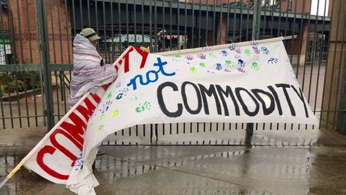 Peoplestown resident Sherise Brown fixes a sign that reads “Community not Commodity” that had been knocked down by the weather outside Turner Field on Monday.J. Scott Trubey/strubey@ajc.com