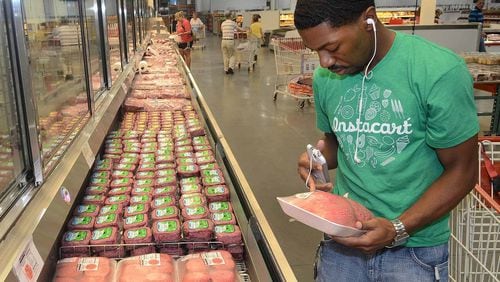Marcus Amison chooses items on his electronic shopping list, then uses a UPC scan program on a smartphone phone to verify the item before putting it in his cart. Amison, 27, is an independent contractor for Instacart. Amison is a chef and augments his income with part-time work for Instacart.