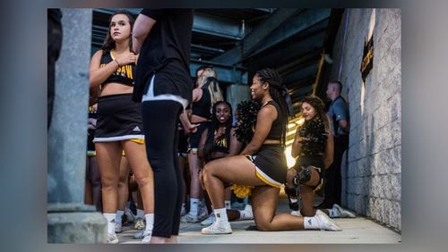 Three cheerleaders are seen kneeling in the tunnel by the field during the national anthem before Saturday's matchup between Kennesaw State and Gardner-Webb, Saturday, Oct. 21, 2017. Four cheerleaders kneeled during the anthem to continue the protests at KSU football games.