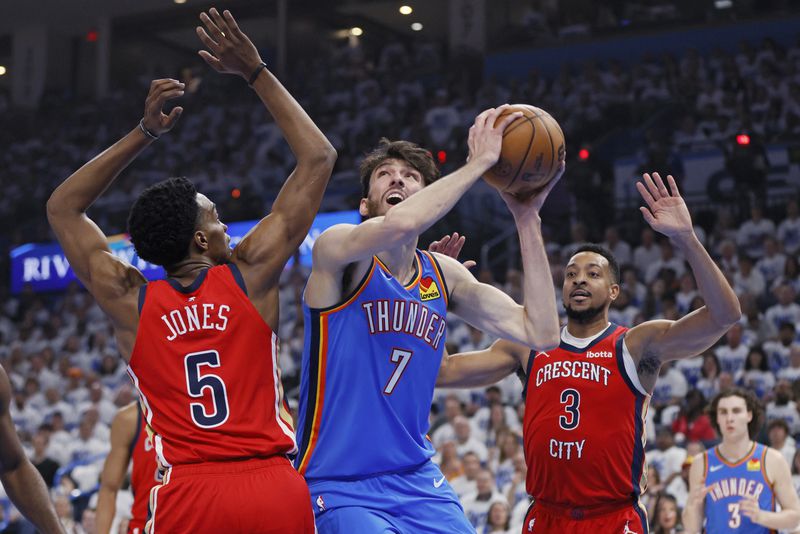 Oklahoma City Thunder forward Chet Holmgren (7) prepares to shoot from between New Orleans Pelicans forward Herbert Jones (5) and guard CJ McCollum (3) during the first half in Game 2 of an NBA basketball first-round playoff series Wednesday, April 24, 2024, in Oklahoma City. (AP Photo/Nate Billings)