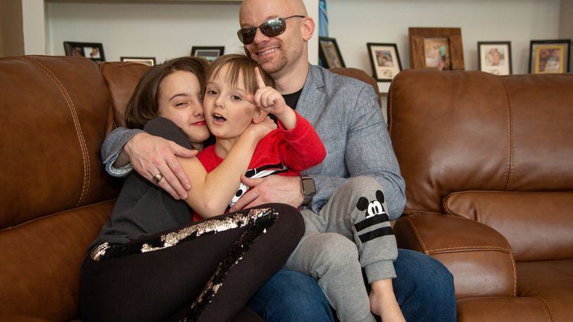 Chad Foster (right) plays with his daughter Juliana, 11, and son Jackson, 3, on the couch in his Marietta home. He is a blind man who is an amazingly successful business person, who skis downhill and who recently gave a motivational speech and his graduation from Harvard business school. After losing his eyesight in his late teens, Chad went on to generate over $45 billion in contracts in the business world currently working for Red Hat in Atlanta, one of the most innovative Tech companies and the world’s largest open source software company; develop software Oracle thought was impossible giving hundreds of millions of people the ability to earn a living by becoming the first to create customer relationship software for the visually impaired. (Photo by Phil Skinner)