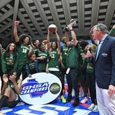 Grayson head coach Geoffrey Pierce holds up the trophy as he celebrates with players after his team defeated McEachern 51-41 Saturday in the Class 7A boys championship game. (Hyosub Shin/hshin@ajc.com)