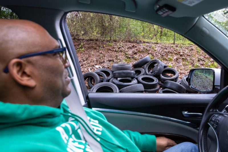 Marc Bolden drives by a discarded pile of tires on Key Road on Monday, March 27, 2023. “The land itself has been neglected. It’s just a wasteland,” said Bolden, a marketing director and former U.S. Marine who leads his neighborhood’s homeowners association. “No one was going to do anything with it. In my opinion, if they build the training center there and they take care of it … and it is actually something useful, it benefits us.” (Arvin Temkar / arvin.temkar@ajc.com)
