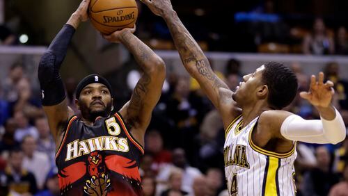 Atlanta Hawks forward Josh Smith, left, shoots over Indiana Pacers forward Paul George during the first half of an NBA basketball game in Indianapolis, Tuesday, Feb. 5, 2013. (AP Photo/Michael Conroy)