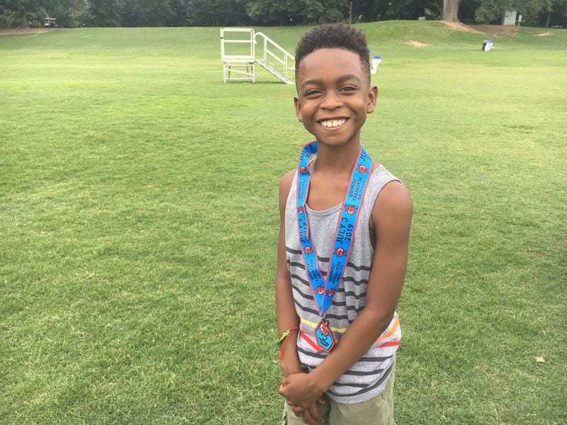 Saleem Yasin, 9, poses after running the Anthem Peachtree Junior on Wednesday, July 3, 2019. (Ben Brasch/AJC)