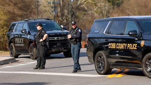 Cobb County police officers blocked an intersection behind McEachern High School as the authorities investigated a shooting in the parking lot of the Powder Springs school on Feb. 1, 2024. (Miguel Martinez / miguel.martinezjimenez@ajc.com)
