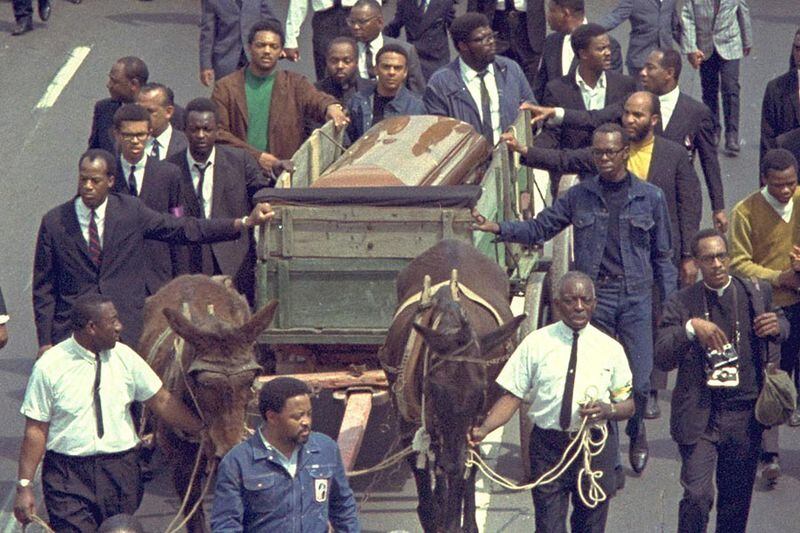 A brace of plow mules drawing the farm wagon bearing the mahogany casket of Dr. Martin Luther King, Jr., makes its way along the funeral procession route on Hunter Street (today’s Martin Luther King Jr. Drive) on  April 9, 1968.  (AP Photo)