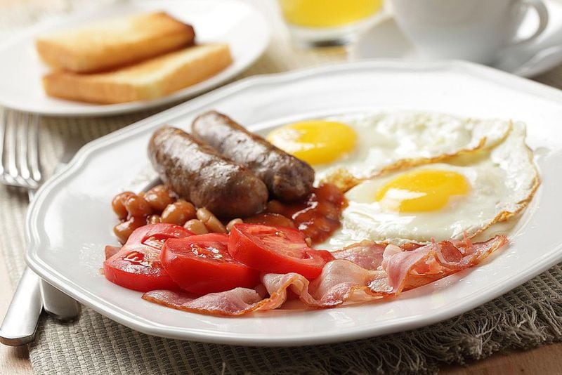 The traditional full English breakfast is an expansive meal, frequently including sausage, bacon, eggs, tomatoes, baked beans and more. (LILYANA VINOGRADOVA / GETTY IMAGES)