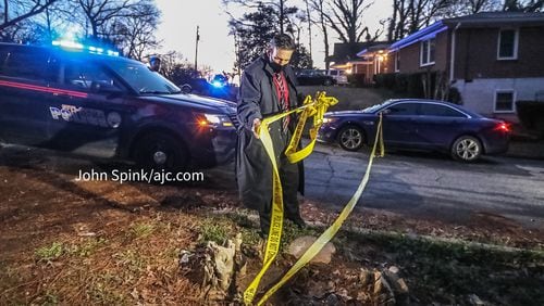 A homicide detective removes crime scene tape on Center Hill Avenue, where the body of a shooting victim was found inside a car that crashed and burned.