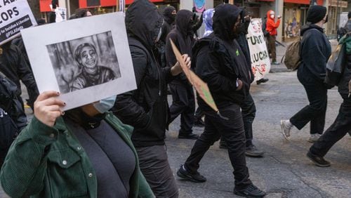 Forest Defender protesters march in the streets near Underground Atlanta Saturday, Jan. 21, 2023. Atlanta Police Department said several people were arrested after a Police car was set afire. 