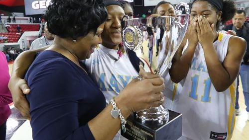 Mays point guard Kamiyah Street gives coach Chantay Frost a hug while handing her the trophy with Sierra Loving (right) looking on after defeating Harrison 52-51 in their Class AAAAAA girls state basketball championship game Thursday, March 9, 2017, in Athens. Curtis Compton/ccompton@ajc.com