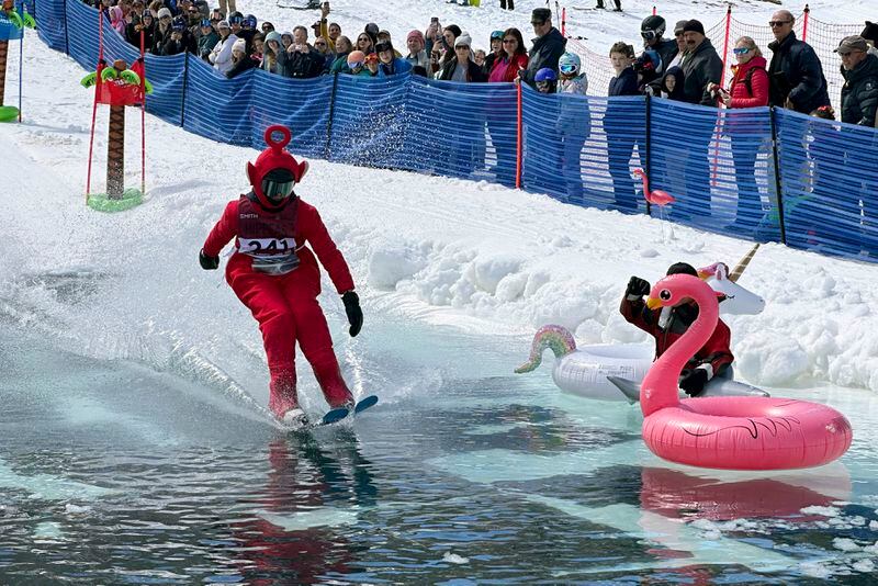A skier dressed as a Teletubbie participates in a pond skimming event at Gunstock Mountain Resort, Sunday, April 7, 2024, in Gilford, N.H. The wacky spring tradition is happening this month at ski resorts across the country and is often held to celebrate the last day of the skiing season. (AP Photo/Nick Perry)