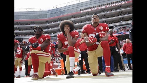 In this Oct. 2, 2016, file photo, from left, San Francisco 49ers outside linebacker Eli Harold, quarterback Colin Kaepernick and safety Eric Reid kneel during the national anthem before an NFL football game against the Dallas Cowboys in Santa Clara, Calif.