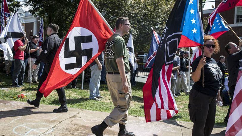 A white nationalist carries a Nazi flag during a protest in Charlottesville, Va., Aug. 12, 2017. (AJC File)