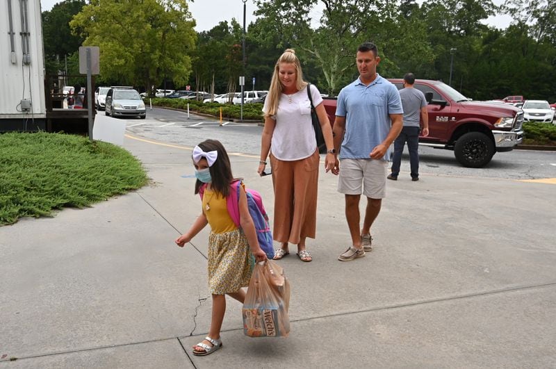 In this file photo, Addie Hicks, kindergartener, makes her way to school as her parents Erin and Eddie Hicks look on the first day of school amid the coronavirus outbreak at Jackson Elementary School in Lawrenceville. Hyosub Shin / Hyosub.Shin@ajc.com)