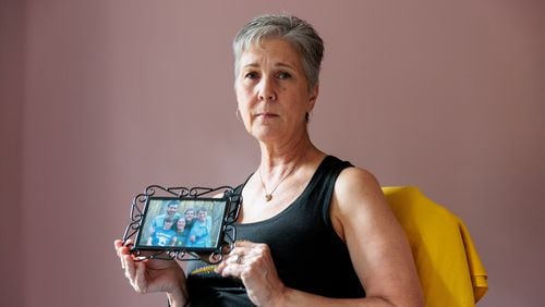 Michelle Cleveland holds a family photo taken the day before her son Thomas, 18, died by suicide. She lost two sons to suicide in 2016. “It’s been six years now, and everything we do is colored by it,” his mother said. “Every choice we make, it’s somehow touched by what happened.” (Arvin Temkar / arvin.temkar@ajc.com)