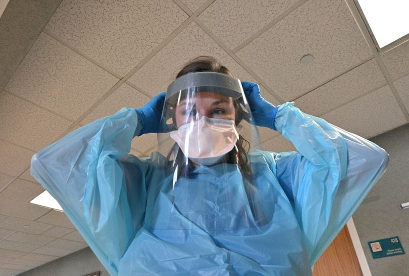 Registered ICU nurse Katie Van Hook puts on PPE before she attends to a COVID-19 patient at Memorial Health's Heart and Vascular Institute in Savannah. By many accounts, Memorial Health has fared better than other hospitals in the region, but the strain of the latest COVID-19 wave has still taken its toll on hospital staff. (Hyosub Shin / Hyosub.Shin@ajc.com)