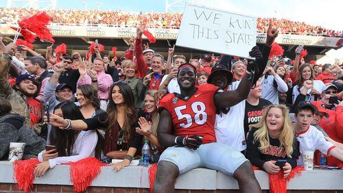 Georgia defensive tackle Sterling Bailey celebrates with UGA fans after beating Georgia Tech 13-7 on Saturday. The Bulldogs have one game remaining this season: a bowl. Curtis Compton / ccompton@ajc.com